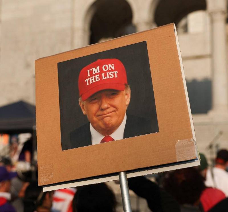 Una persona sostiene una fotografía del presidente Donald Trump con un sombrero rojo que dice “Estoy en la lista” frente al Ayuntamiento de Los Ángeles. FOTO: AFP. 