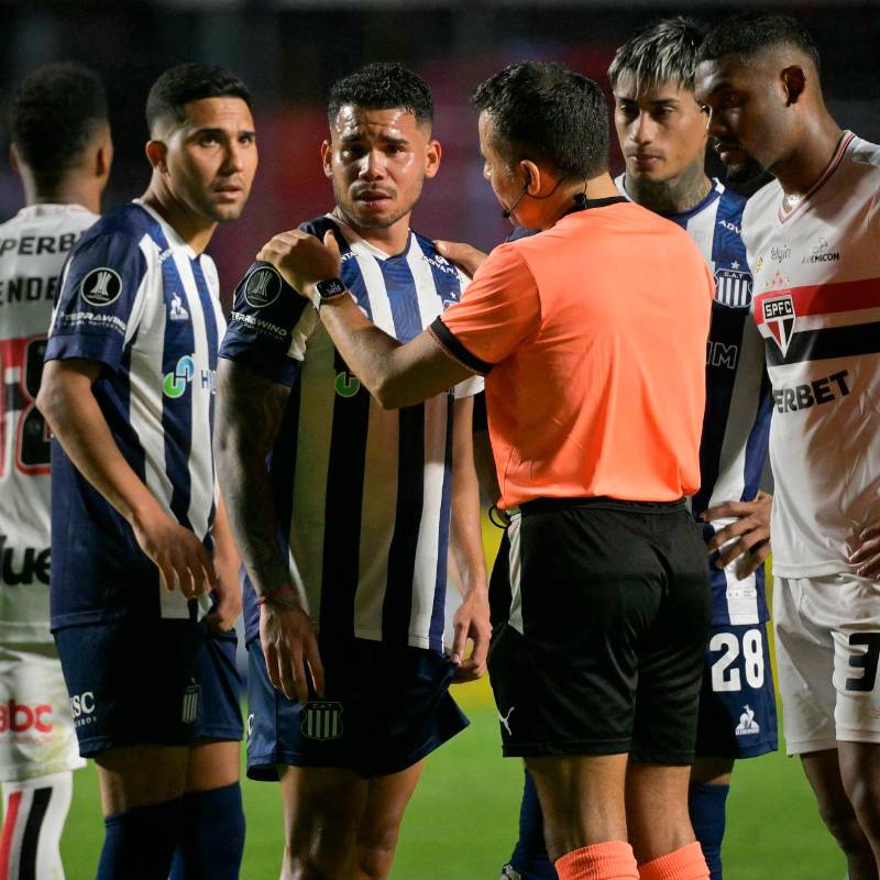 Miguel Navarro, de Talleres, junto al árbitro chileno Piero Maza. FOTO: AFP