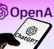 En primer plano, un celular con la aplicación de ChatGPT. Al fondo, la empresa OpenAI, los dueños de la IA mencionada. FOTO: DEPOSITPHOTOS
