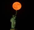 La Luna llena del esturión sale detrás de la Estatua de la Libertad en la ciudad de Nueva York. Foto: GETTY