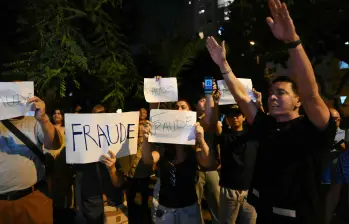 Manifestantes muestran carteles que dicen “Fraude” mientras participan en una protesta tras los primeros resultados de la elección presidencial frente a la sede del Jurado Nacional de Elecciones (JNE) en Lima. Foto: AFP
