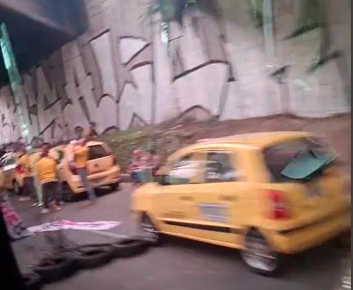 Los taxistas bloquean con sus vehículos y con llantas la vía, dando paso intermitente a un solo carril. FOTO: TOMADA DE VIDEO Los taxistas bloquean con sus vehículos y con llantas la vía, dando paso intermitente a un solo carril. FOTO: TOMADA DE VIDEO
