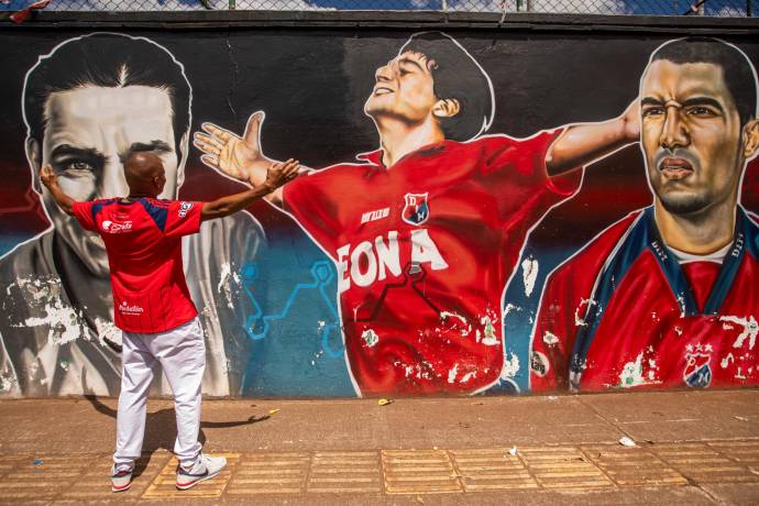 Un hincha del Deportivo Independiente Medellín posa frente a uno de los murales que hay del equipo en la ciudad. FOTO: CARLOS VELÁSQUEZ 