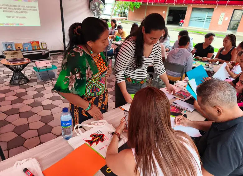 En compañía de Mileidy Cuéllar, indígena guna, Carmen Blanco revisa el trabajo de los asistentes al taller sobre molas. FOTO CORTESÍA