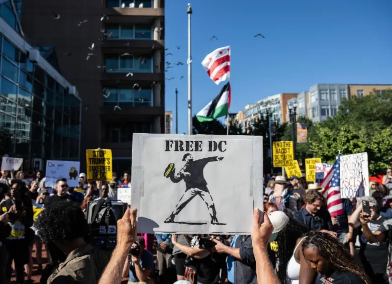 Una persona sostiene un cartel durante una manifestación contra el despliegue de la Guardia Nacional y el aumento de las redadas de inmigración en Washington. FOTO: AFP