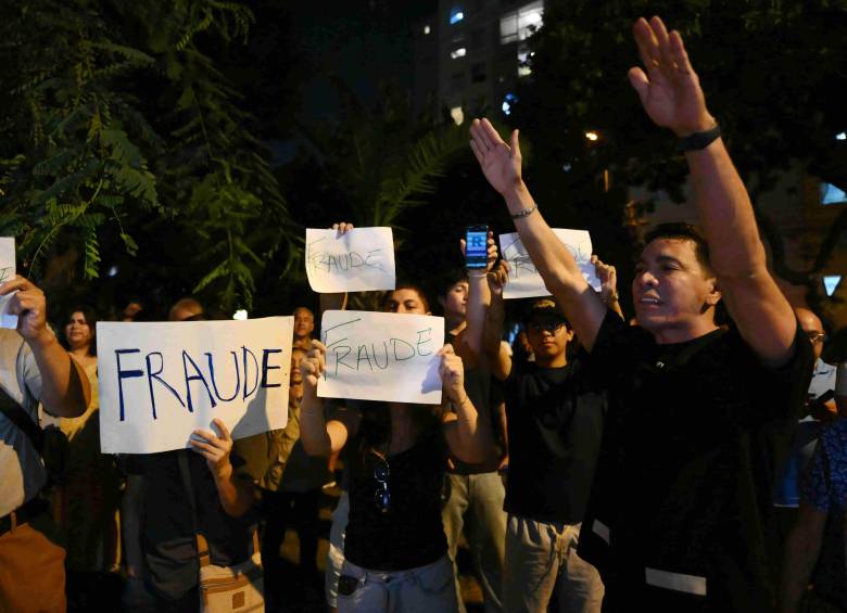 Manifestantes muestran carteles que dicen “Fraude” mientras participan en una protesta tras los primeros resultados de la elección presidencial frente a la sede del Jurado Nacional de Elecciones (JNE) en Lima. Foto: AFP