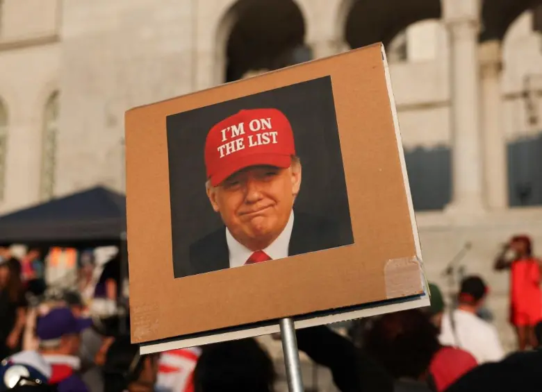 Una persona sostiene una fotografía del presidente Donald Trump con un sombrero rojo que dice “Estoy en la lista” frente al Ayuntamiento de Los Ángeles. FOTO: AFP. 