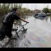 AP - Un hombre empuja su bicicleta por una calle inundada en La Plata, provincia de Buenos Aires.