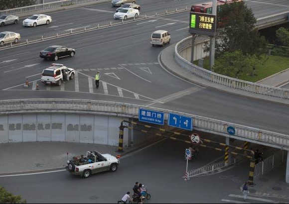 AP - 29 de mayo 2014. Un auto lleno de polic&#237;as cruza por el mismo puente en Beijing.