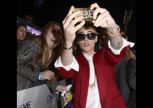 AP - El cantante Justin Bieber ayuda a una fan&#225;tica a tomarse una foto selfie en pleno estreno de su pel&#237;cula en Los &#193;ngeles.