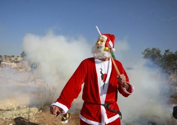 AP - Un protestante palestino usa un disfraz de Pap&#225; No&#233;l durante una manifestaci&#243;n cerca a Ramallah.