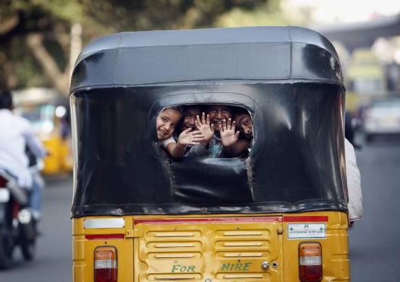 AP - Peque&#241;os ni&#241;os en La India saludan a los viajeros desde al ventana trasera de un auto rickshaw.