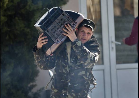 AP - Este aviador ucraniano lleva un televisor con &#233;l. El hombre deja la base a&#233;rea Belbek, Crimea.