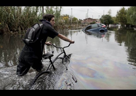 AP - Un hombre empuja su bicicleta por una calle inundada en La Plata, provincia de Buenos Aires.