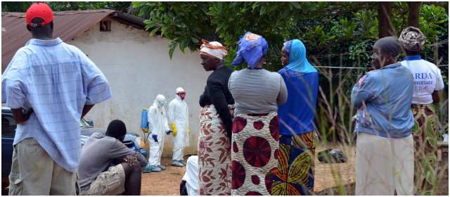 Algunos residentes miran a los trabajadores de salud de la Cruz Roja de Liberia, que llevan traje de protección para desinfectar un patio después de retirar el cuerpo de una víctima del virus del Ébola. FOTO AFP