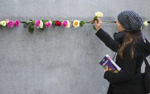 Algunos berlineses colocaron rosas y prendieron velas en los fragmentos del Muro de Berlín que aún se conservan. FOTO REUTERS
