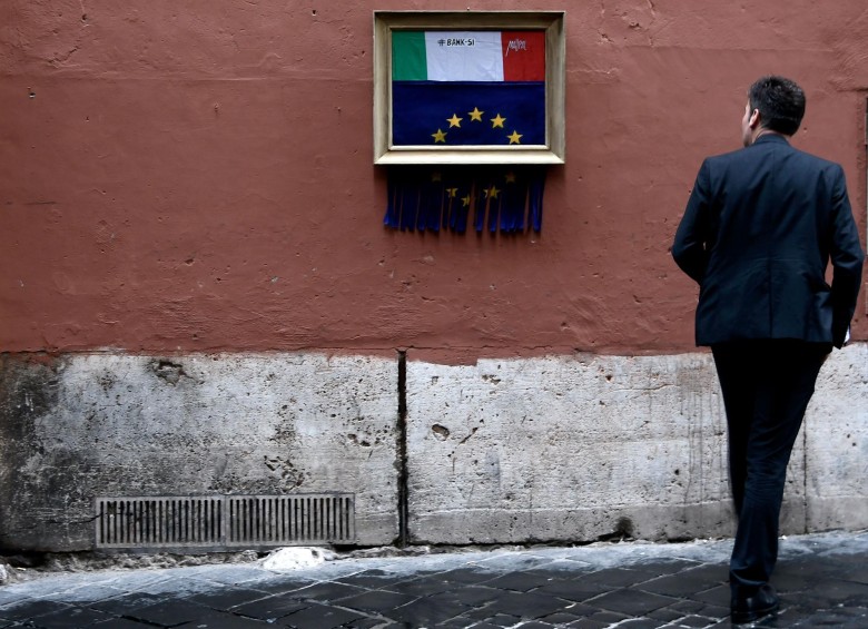 11 de octubre. Un hombre en el centro de roma mira una instalación inspirada en Banksy en la que se ve la bandera europea siendo triturada mientras descubre la del país mediterráneo. Arriba dice “Bank-si”. Foto: Afp