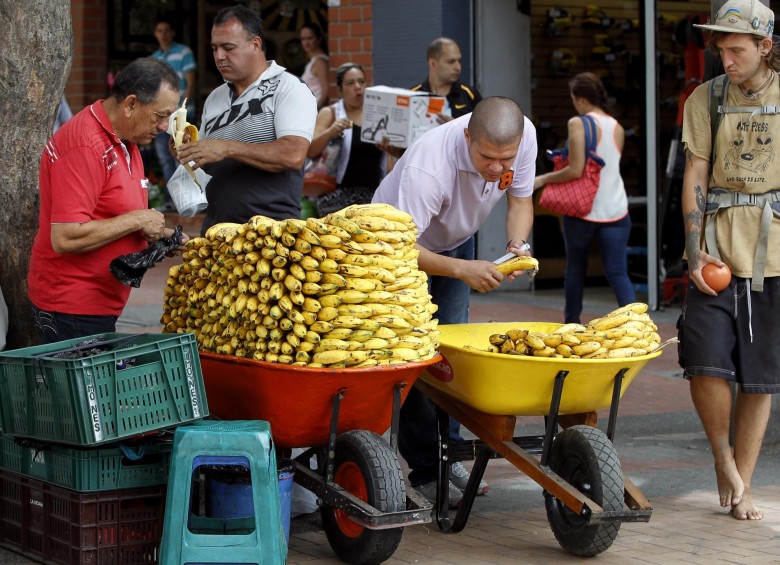 Julio César Piedrahita lleva 19 años vendiendo bananos en su carretilla; Andrés Mendes Durango, cuatro meses llevando el aroma del café. Trabajan sin prestaciones. FOTOS Jaime Pérez