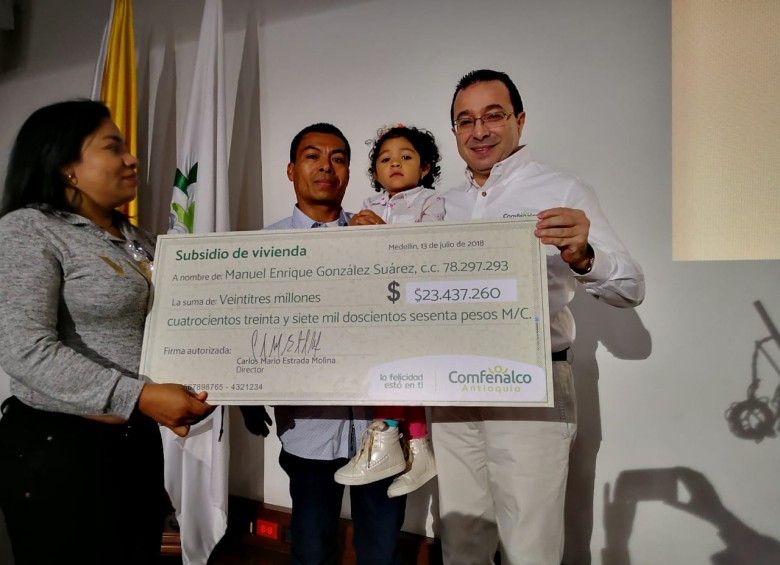 El director de Comfenalco, Carlos Mario Estrada, (a la derecha en la foto), entrega el subsidio a una de las familias beneficiarias. FOTO CORTESÍA