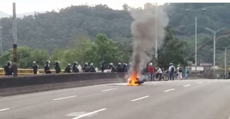 Moto en llamas sobre el puente de Barranquilla (carrera 67) durante los disturbios en la U. de A. FOTO CORTESÍA