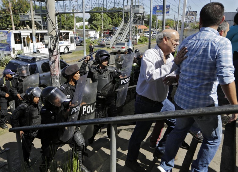 Carlos Chamorro, director de Confidencial, el medio allanado por el gobierno, es retirado por antimotines de las instalaciones de la Policía, a donde fue el sábado a reclamar por lo sucedido. FOTO afp