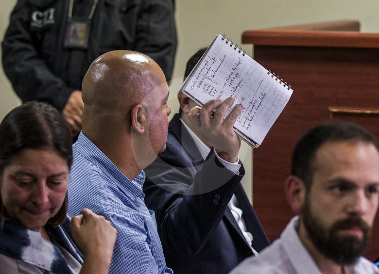 Durante las primeras audiencias, el alcalde Cardona intentó ocultarse de las cámaras usando su libreta. FOTO jaime pérez