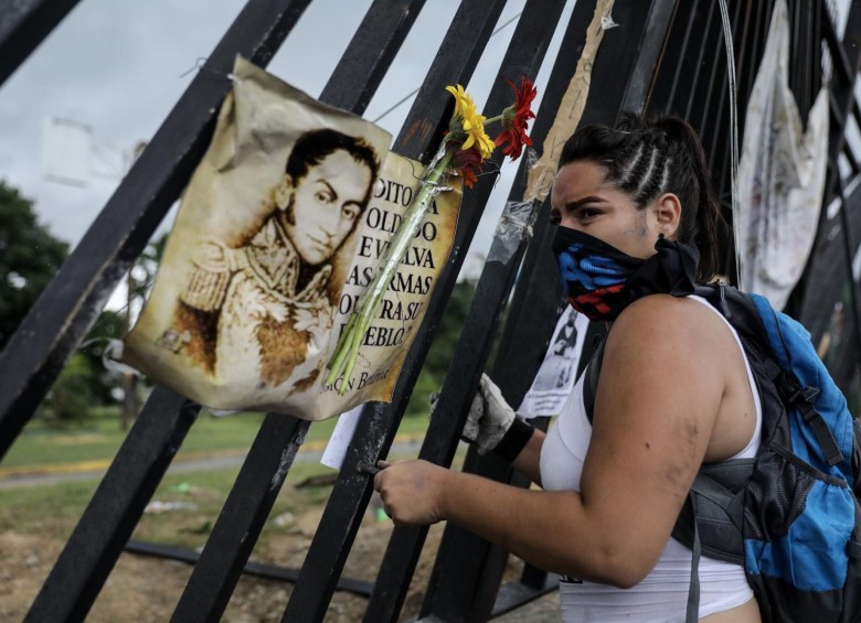Las rejas de la Base Aérea Francisco de Miranda, fueron el lugar para colgar sus mensajes al gobierno. En la imagen una joven cuelga el retrato de Simón Bolívar. FOTO: EFE