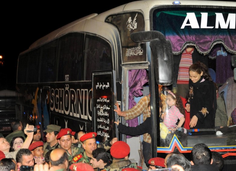 Varios civiles bajan de un autobús a su llegada a Damasco (Siria) tras la liberación de los miles de prisioneros. FOTO EFE 