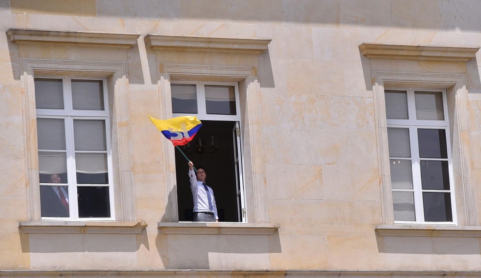 Desde una ventana de la Casa de Nariño, un hombre agitó una bandera de Colombia con el Sí a la paz. FOTO AFP