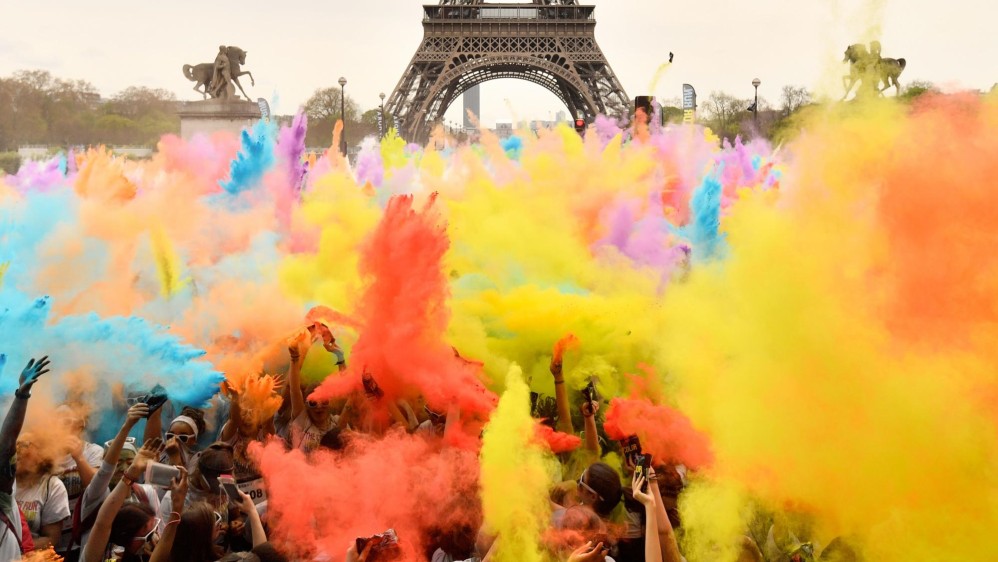 La gente arroja polvo de colores mientras celebran la finalización de sus cinco kilómetros en el Color Run 2018. Foto: CHRISTOPHE SIMON