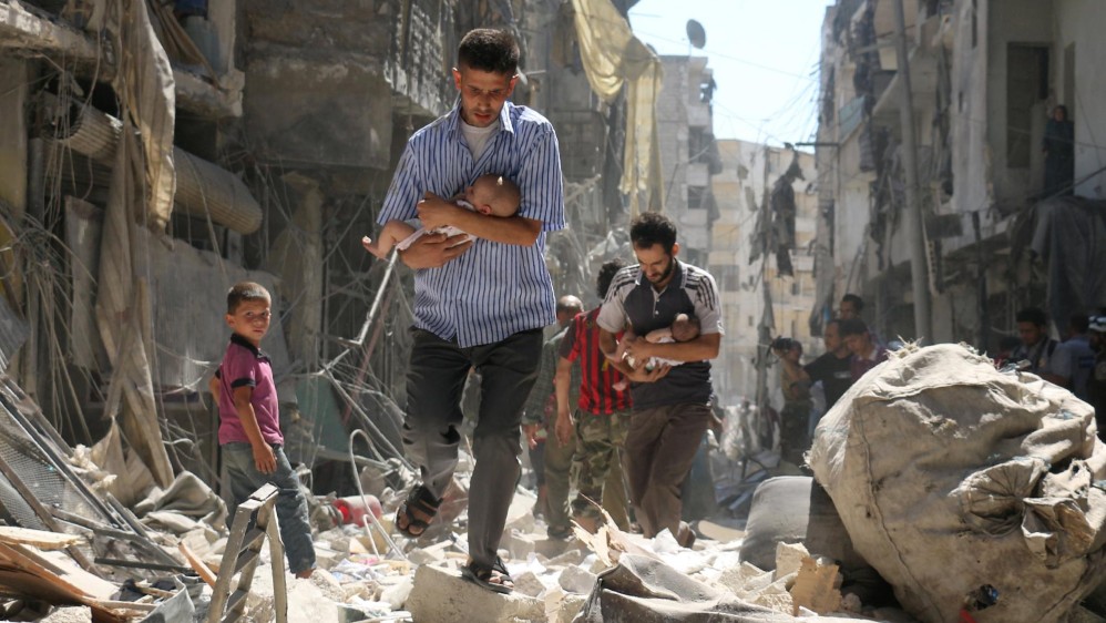 Hombres sirios con unos bebés en brazos se abren camino a través de los escombros de edificios destruidos tras un ataque aéreo en el barrio de Salihin de Alepo. Segundo lugar noticias. FOTO Ameer Alhalbi, Agence France-Presse / Cortesía de World Press Photo Foundation
