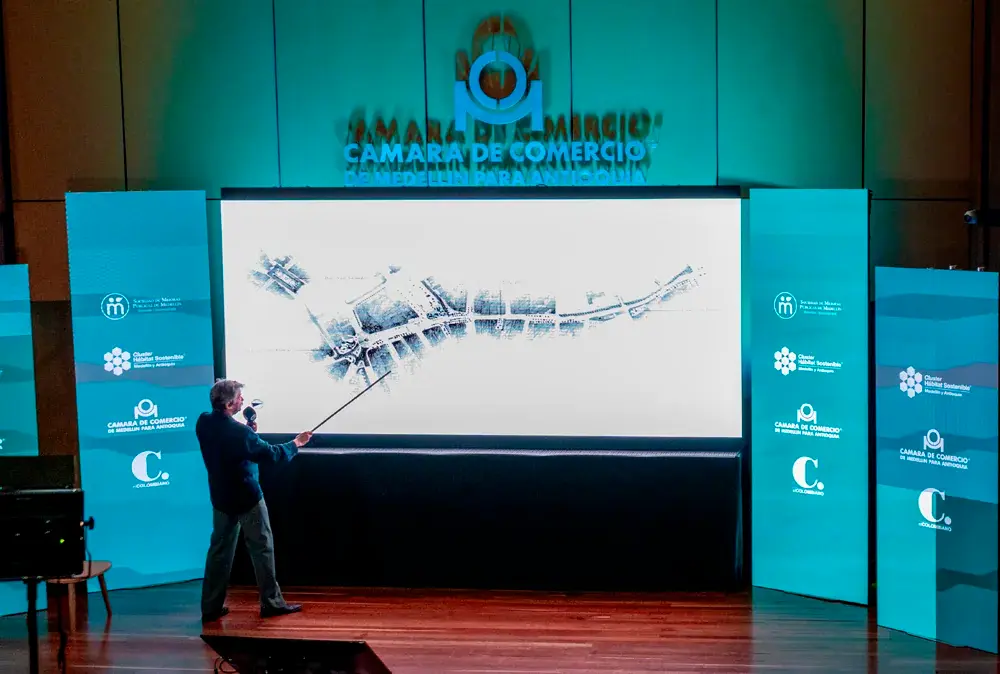 Con un puntero, Jorge Mario Jáuregui señala las áreas críticas y las oportunidades de intervención identificadas en los diagnósticos urbanos, trazando la ruta para la visión compartida del Centro de Medellín.