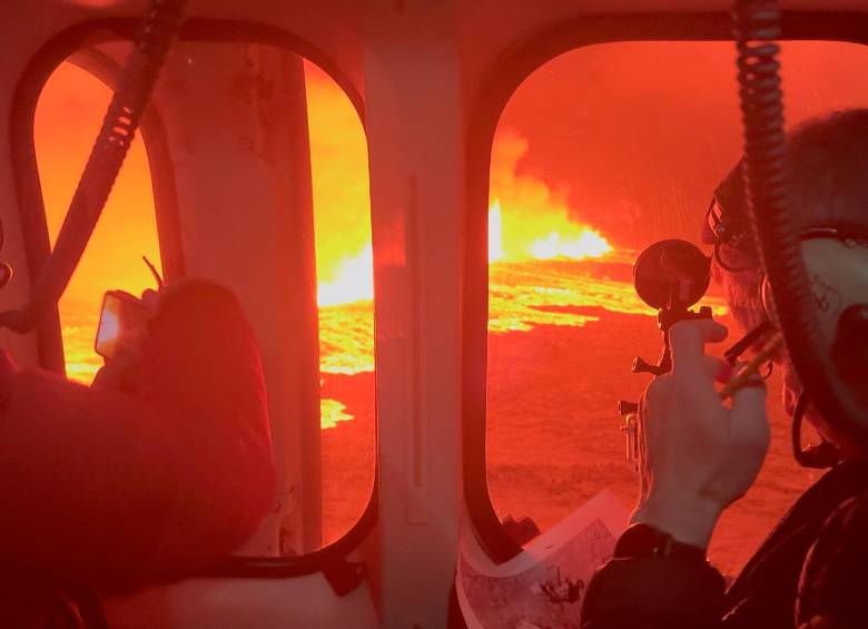 Personal de emergencia y a científicos en un helicóptero de la Guardia Costera de Islandia sobrevolando una erupción volcánica en la península de Reykjanes, a 3 km al norte de Grindavik. FOTO AFP