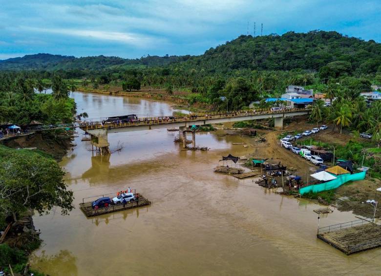 Desde el extremo occidental del río, un grupo de hombres vigila la operación de los planchones, que pueden llegar a ser entre 11 y 15, mientras estos atraviesan el crecido río. FOTO Camilo Suárez.