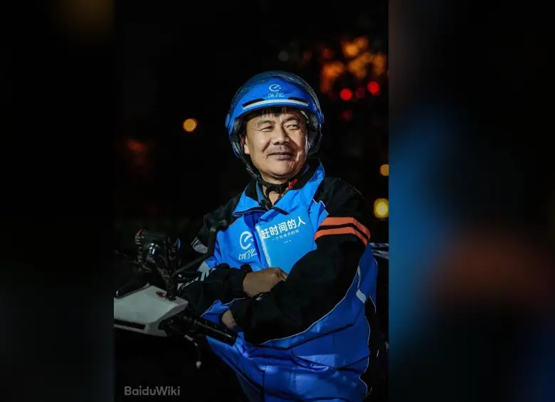 El repartidor chino Wang Jibing, de 56 años, sostiene un ejemplar de su libro de poemas mientras trabaja. En julio de 2026 ganó el Premio Literario Lu Xun, uno de los más importantes de China. / Foto: BaiduWiki 