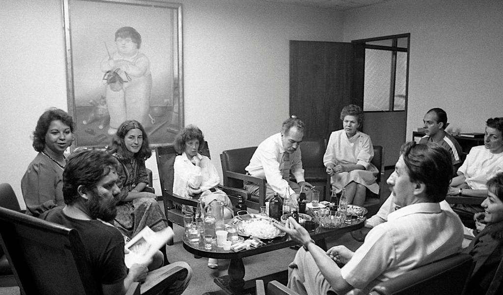 Reunión en la dirección de la Piloto. En los extremos Luis Fernando Peláez y Miguel Escobar. A la izquierda, Gloria Palomino, Tita Maya, Luz Mercedes Cadavid, María José Rodríguez. Manuel, entre todos. Foto Jairo Osorio, del libro iconográfico Manuel revelado.