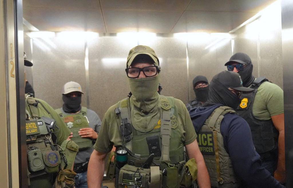 Agentes federales de inmigración patrullando los pasillos de un edificio federal. FOTO: AFP