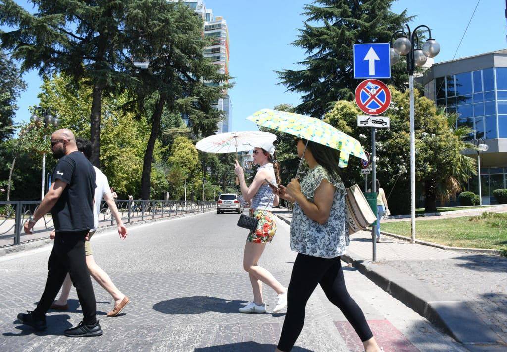 Las personas van con sombrillas debido al intenso calor. FOTO: AFP