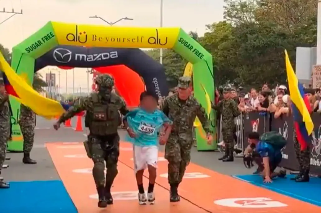Este es el momento en el que los soldados ayudan al niño de 10 años, a cruzar la meta en la Maratón del Valle. FOTO PANTALLAZO 