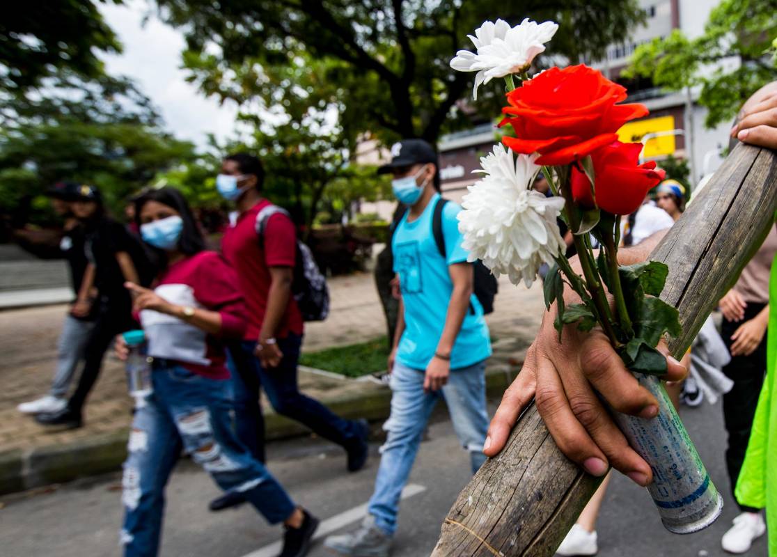 Uno de los jóvenes sostiene un casquillo de una granada lacrimógena lanzada en 2021. Las flores simbolizaron que querían marchar en paz. Foto: JULIO CÉSAR HERRERA