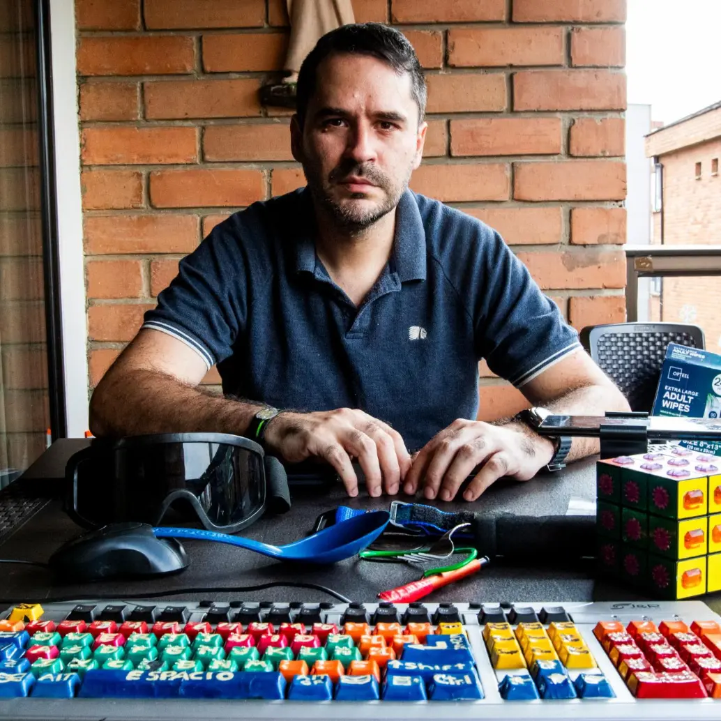 Felipe Betancur y algunos de sus inventos, entre ellos, el “mouse para pie” que tiene como base un cucharón plástico de cocina. FOTO Julio César Herrera.