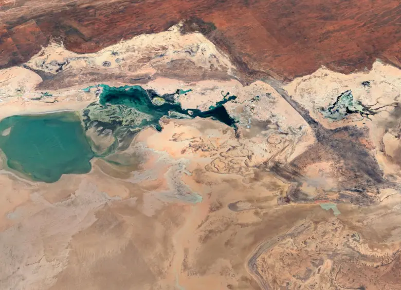 Vista aérea del paisaje desértico en Australia Occidental, capturada por Google Earth, donde contrastan las lagunas turquesa con las formaciones rocosas y los tonos ocres del terreno. FOTO cortesía Google Earth