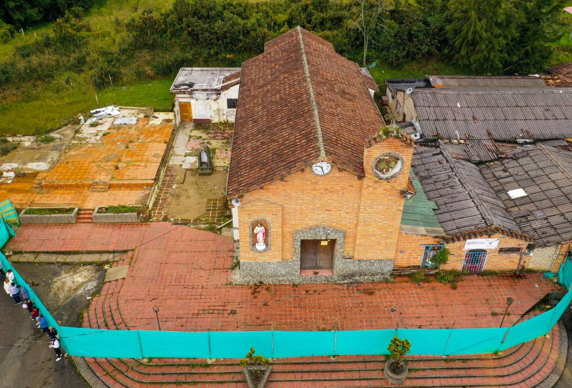 Han pasado cuatro años desde que aparecieron las grietas. El atrio está invadido de maleza y una lona verde circunda la iglesia. Foto: MANUEL SALDARRIAGA QUINTERO.