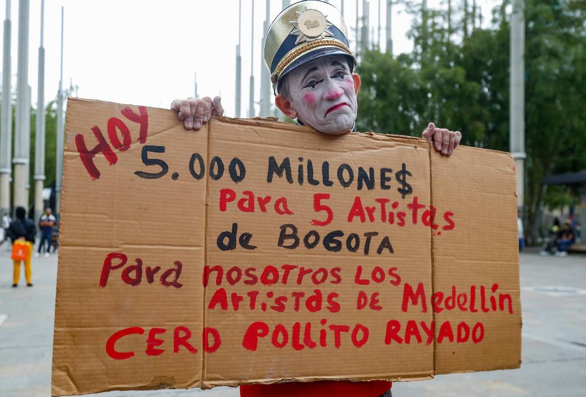 El clown Álvarez mientras sostiene un trozo de cartón con un mensaje que critica el dinero gastado por EPM en el concierto de apertura del Alumbrado. Foto: Manuel Saldarriaga Quintero.