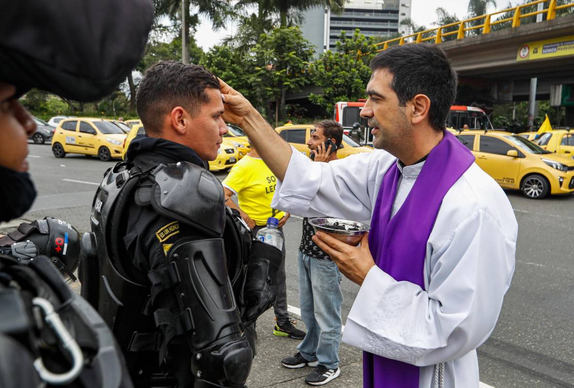  Mientras cumplen con su labor de mantener el orden en la ciudad el presbítero Juan Felipe Escobar impone la ceniza a miembros del Esmad. Foto: MANUEL SALDARRIAGA QUINTERO.