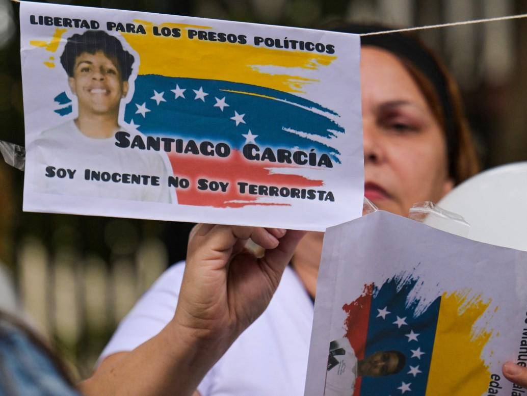 Una mujer cuelga fotografías de presos políticos en una cuerda durante una vigilia exigiendo su liberación frente a la Corte Suprema de Justicia en Caracas. FOTO: AFP