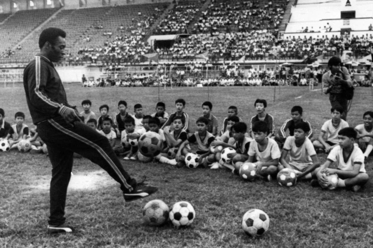En esta foto tomada el 6 de diciembre de 1974 en Bangkok, se ve al jugador de fútbol brasileño Pelé durante una sesión de entrenamiento con niños como parte de un viaje comercial en Tailandia. Foto: Getty