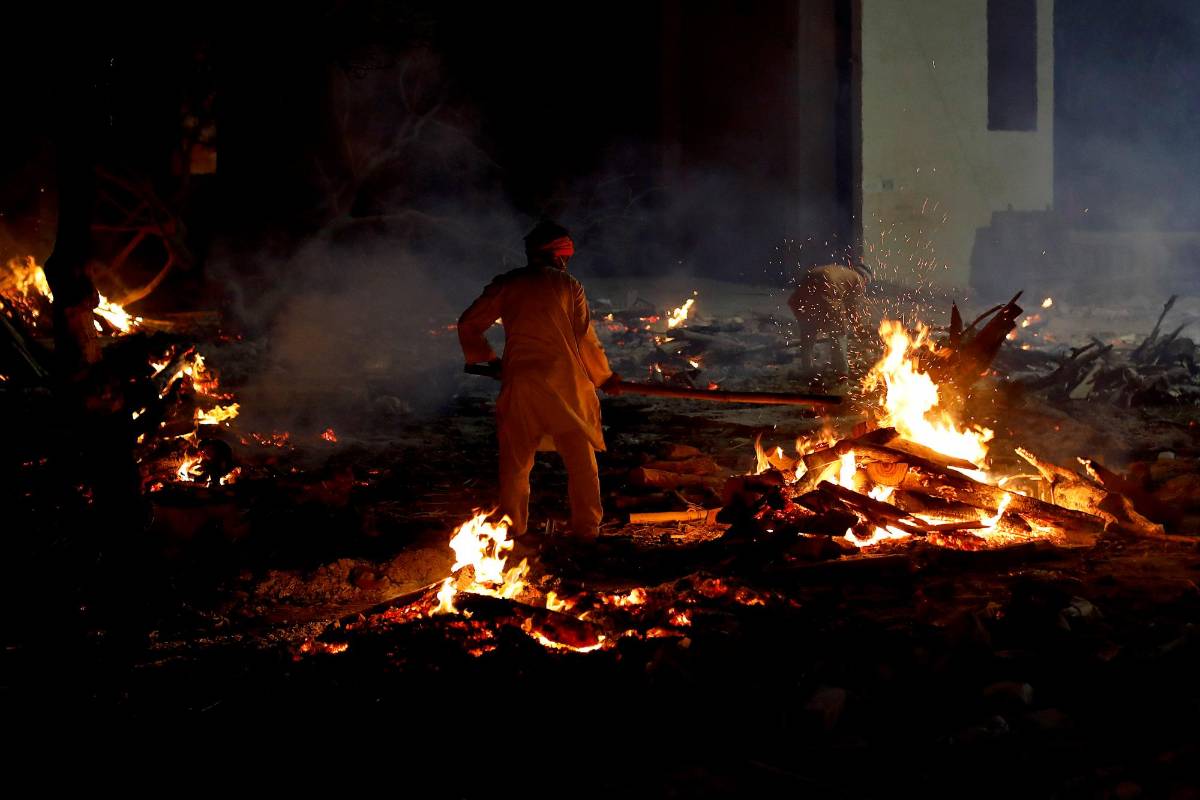 Uno de los familiares espera para realizar los últimos ritos para la víctima del covid-19 en un campo de cremación en Nueva Delhi, India. Foto EFE