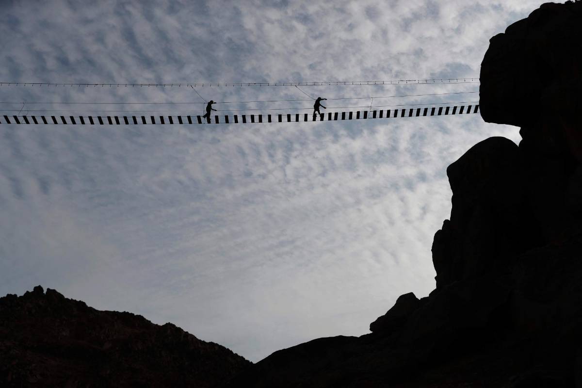 El puente colgante de tablas se encuentra en lo alto de un cerro desde el que se divisan miles de casas. Foto: EFE
