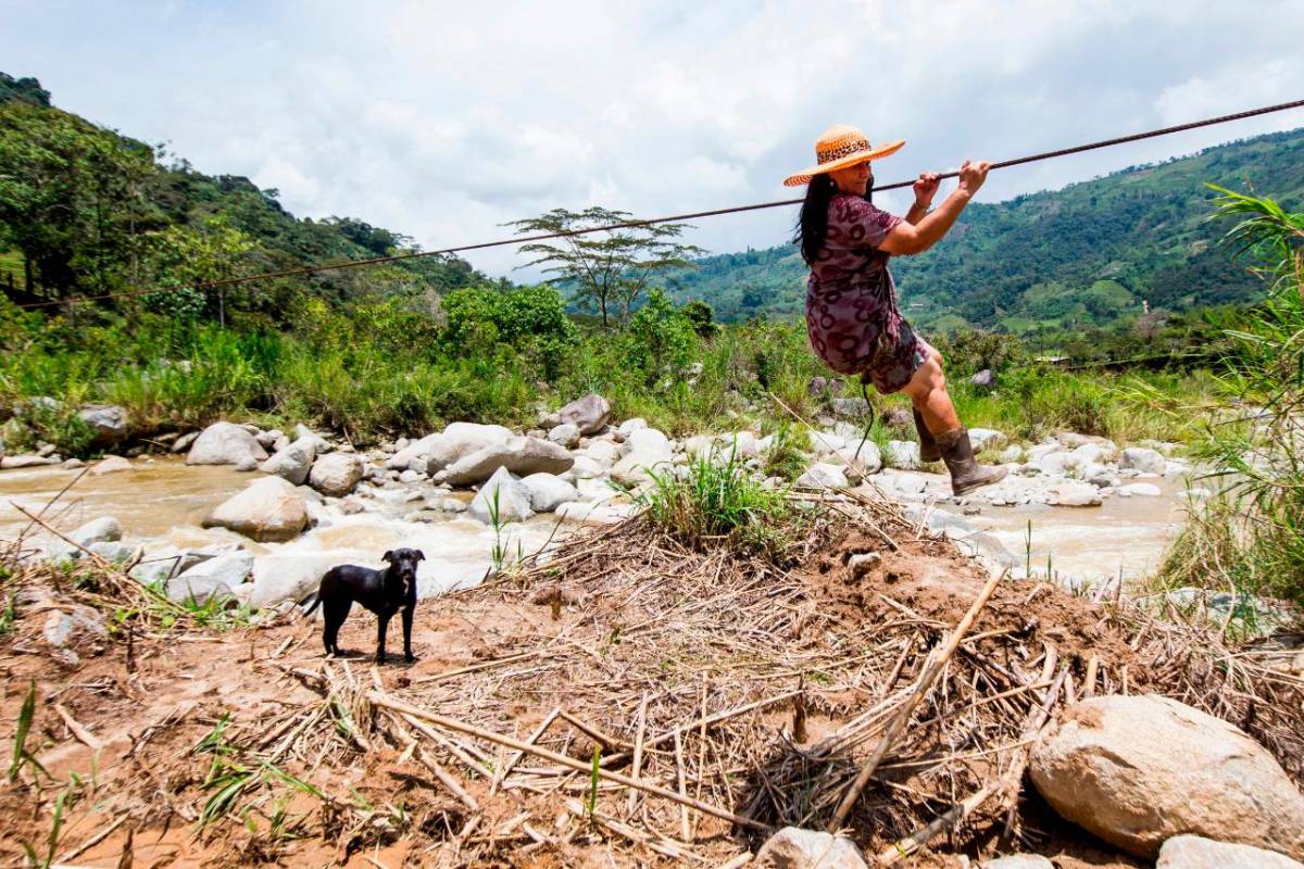 Adultos y niños arriesgan la vida diariamente para cruzar un río que no tiene paso por un puente peatonal. FOTO JULIO CÉSAR HERRERA